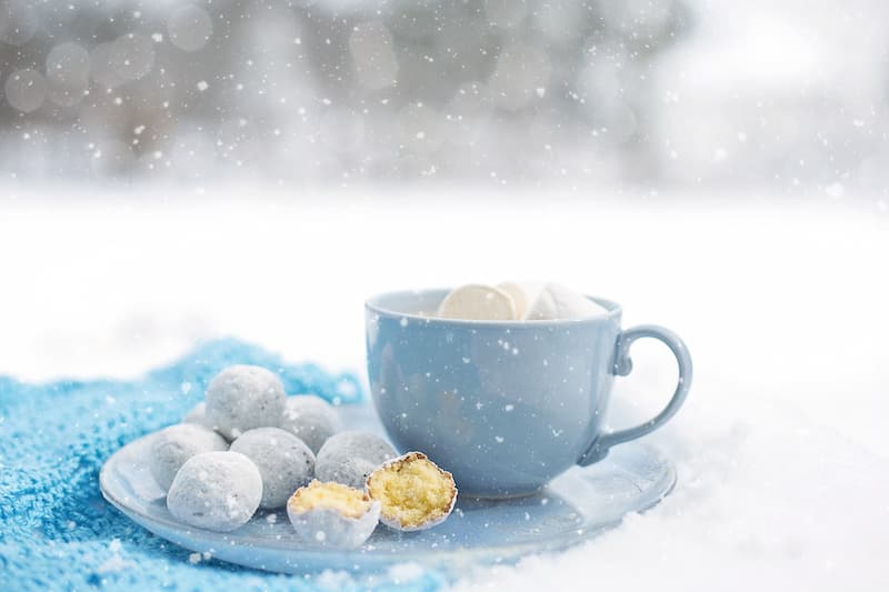 雪の上に置かれたコーヒーカップとお菓子